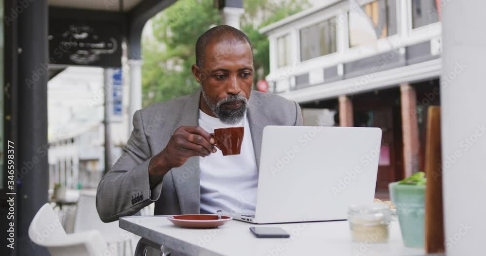 African American man drinking a coffee and using a laptop African American man drinking a coffee and using a laptop