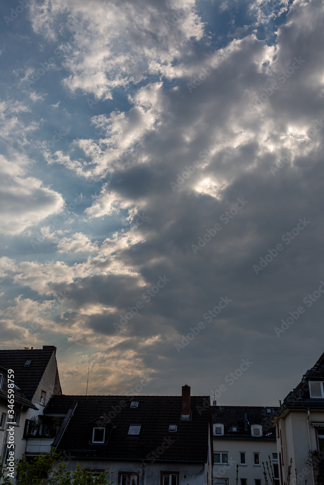 Sunset with cloudy dramatic sky and house roofs
