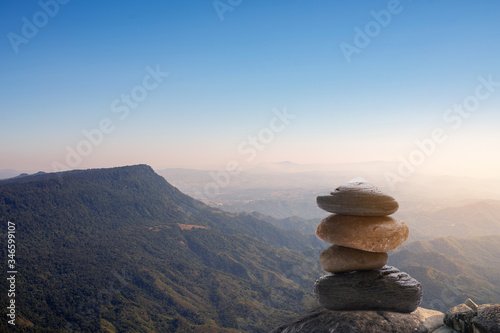 Stack of stones covered with moss on top of the mountain on a background of mountains covered with forests. Concept of balance and harmony. Stack of zen stones. Teamwork balance concept.