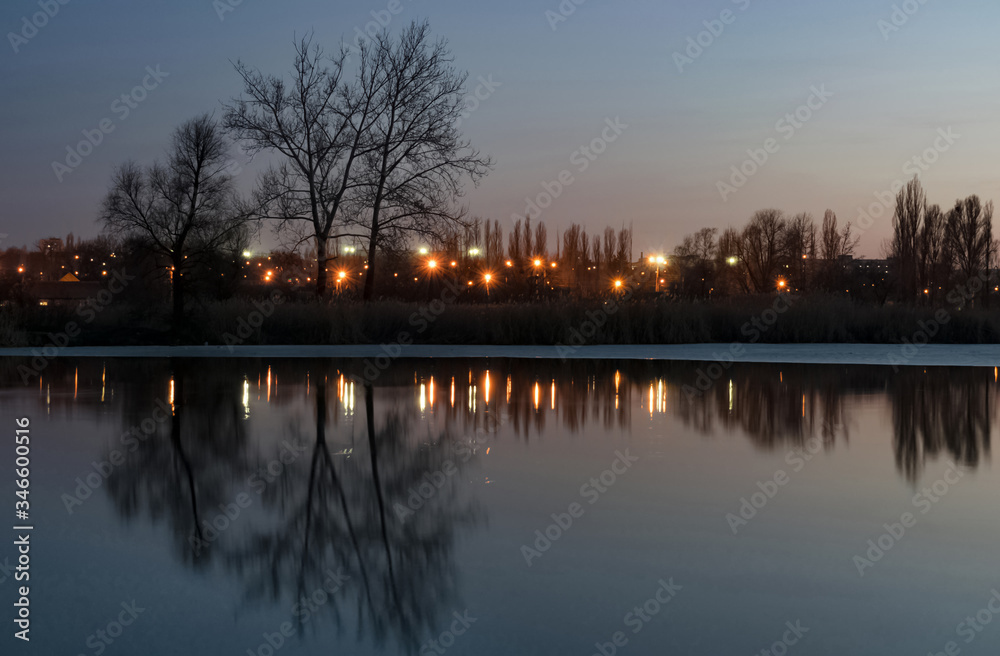 Evening autumn landscape on the shore of a pond with lanterns and reflection