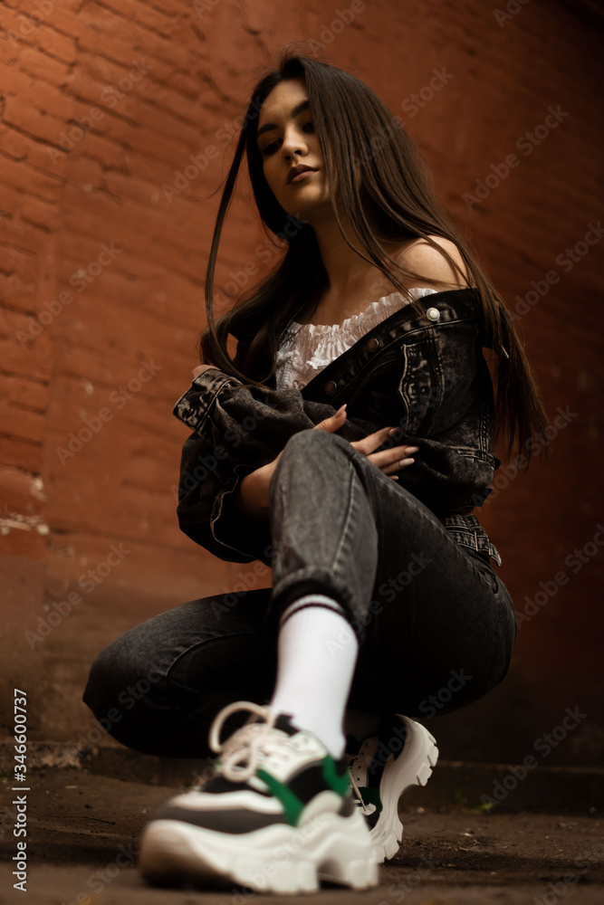 the girl is sitting against a brick wall, the view from below