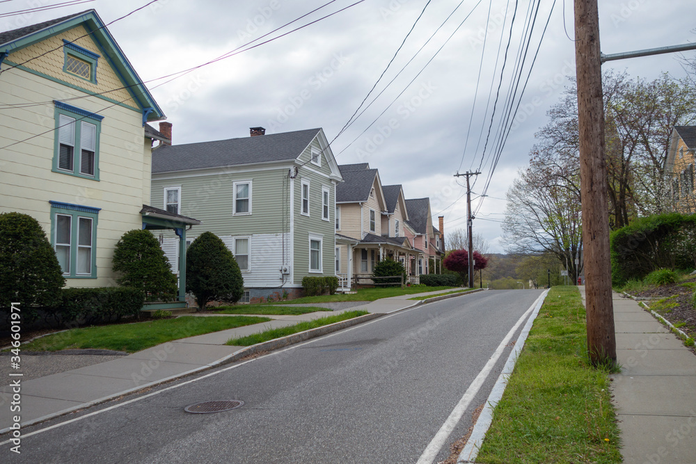 row of homes on a quite suburban street road wth sidewalks and spring budding streets