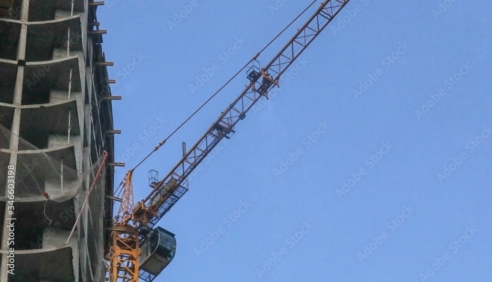 Tower cranes constructing a new residential building. Construction work site and high rise building against blue sky. Construction company or buildings industry concept Tower cranes constructing a new residential building. Construction work site and high rise building against blue sky. Construction company or buildings industry concept