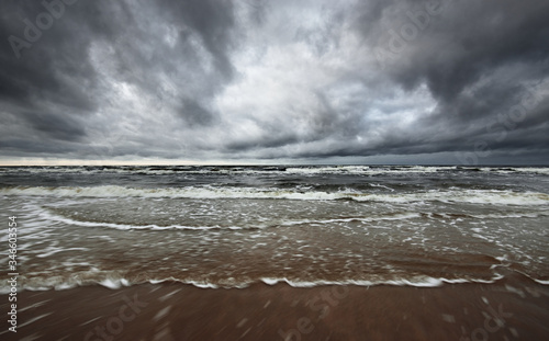 Fototapeta Naklejka Na Ścianę i Meble -  Storm clouds above the North sea in winter, long exposure. Dramatic sky, waves and water splashes. Dark seascape. Netherlands