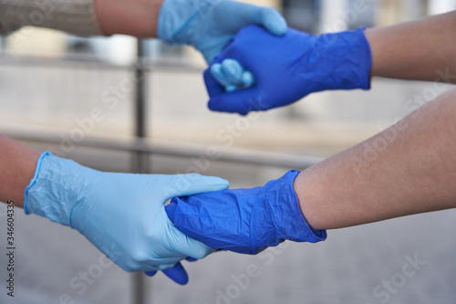 Human hands in protective gloves against covid-19 coronavirus pandemic, handshake in quarantine outdoors in city © Alexander