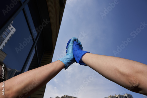 Human hands in protective gloves against covid-19 coronavirus pandemic, handshake in quarantine outdoors in city