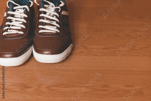 Man's shoes, casual, brown, with white laces, on wooden floor © Robert Petrovic
