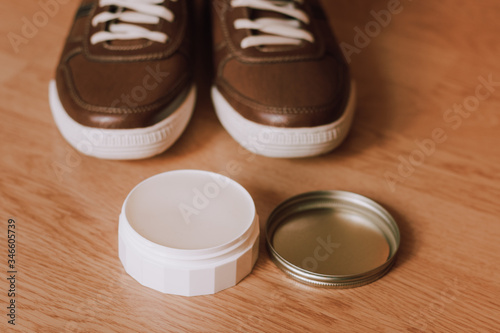 Taking care of shoes. Package of wax in front of casual, modern men's shos in blurred background. photo