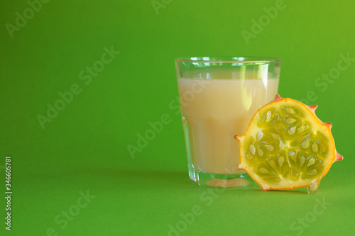 Kiwano slice, exotic vegetable cucumis metuliferus and a glass of fruit juice on a green background. Soft focus. Vegetarian food. photo