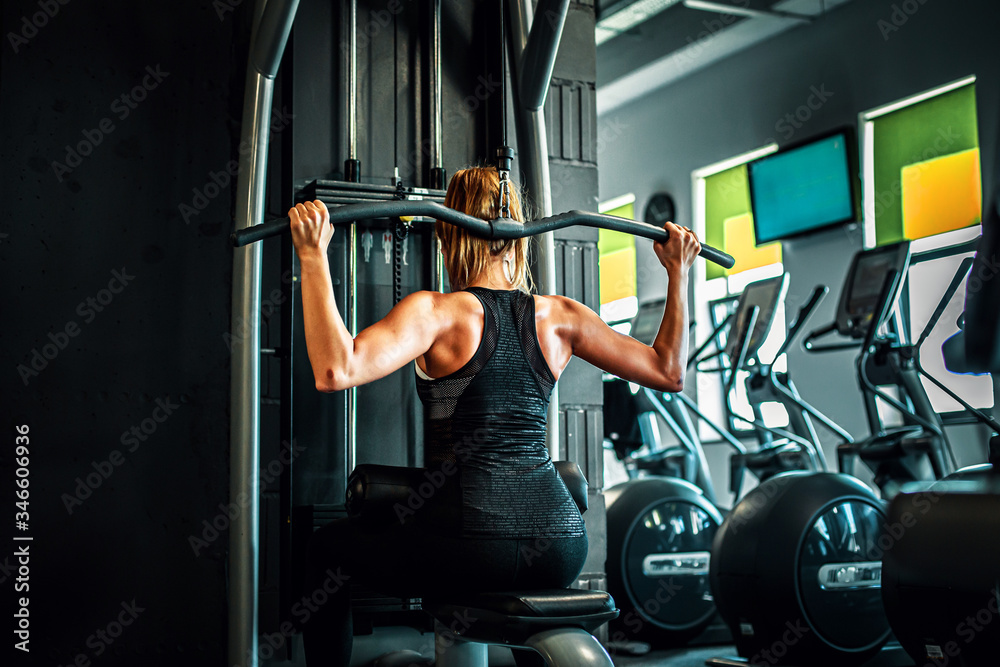 Naklejka premium Kobieta trenująca na siłowni, mięśnie pleców. 