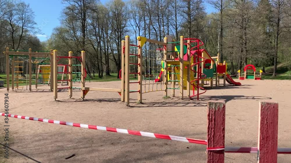 The playground is fenced with a red and white ribbon in the park during quarantine during the coronavirus pandemic in the world, there are no children on the site, access is closed The playground is fenced with a red and white ribbon in the park during quarantine during the coronavirus pandemic in the world, there are no children on the site, access is closed