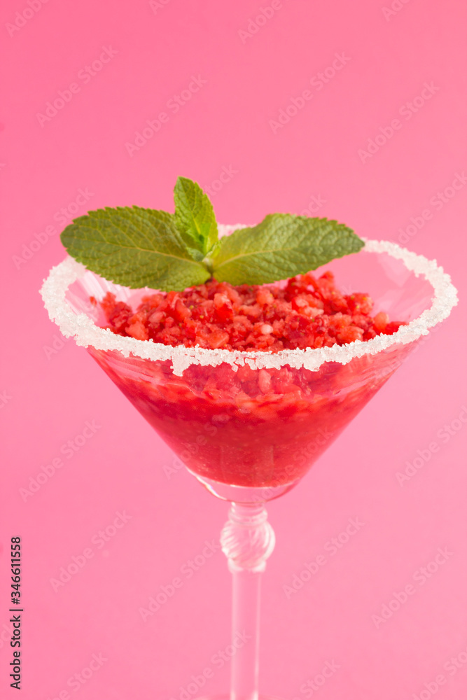 Frozen juice with strawberry in a one martini glass on the pink background. Location vertical. Closeup. Frozen juice with strawberry in a one martini glass on the pink background. Location vertical. Closeup.