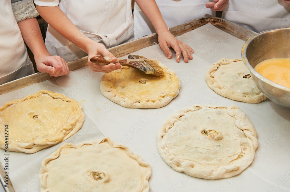 small children grease a dough product with an egg. Holding a brush