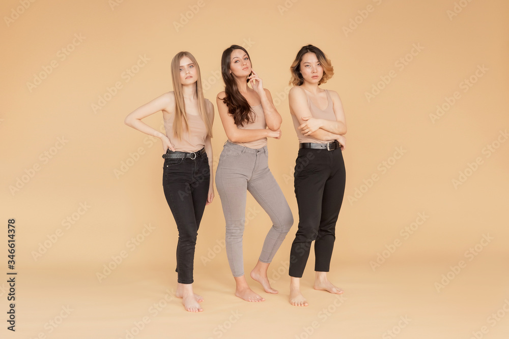 Fototapeta premium Happy young women multicultural Asian, Caucasian standing on beige background. Beauty spa treatment skin care concept