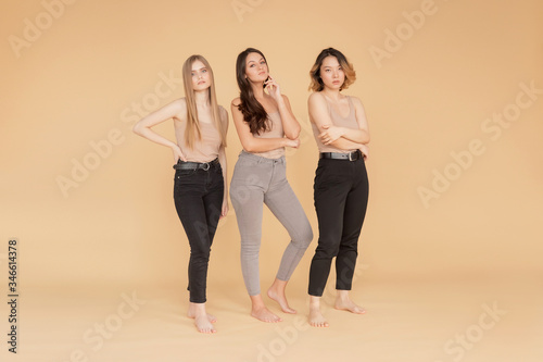 Happy young women multicultural Asian, Caucasian standing on beige background. Beauty spa treatment skin care concept