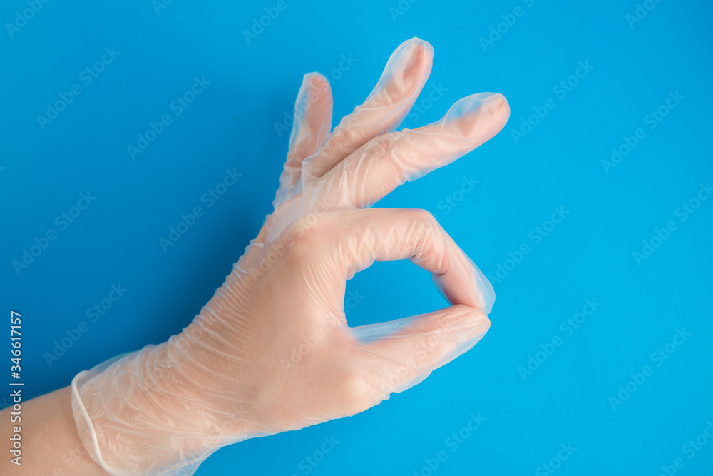 Doctor hand in Medical Latex Glove making OK Sign on blue background