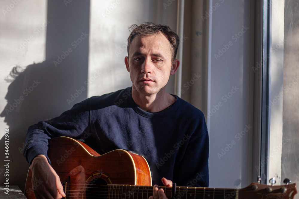 Obraz premium Guy with a guitar near the window.