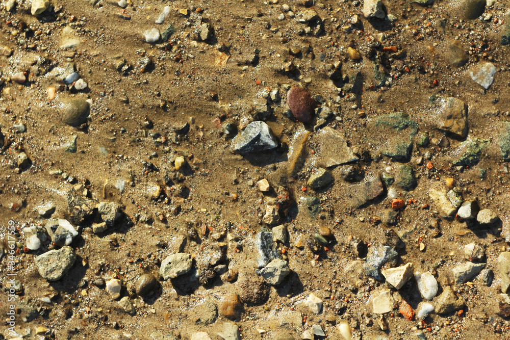 Small stones and sand. The natural texture of the soil. Shore of a reservoir with a beach and pebbles. Small stones and sand. The natural texture of the soil. Shore of a reservoir with a beach and pebbles.