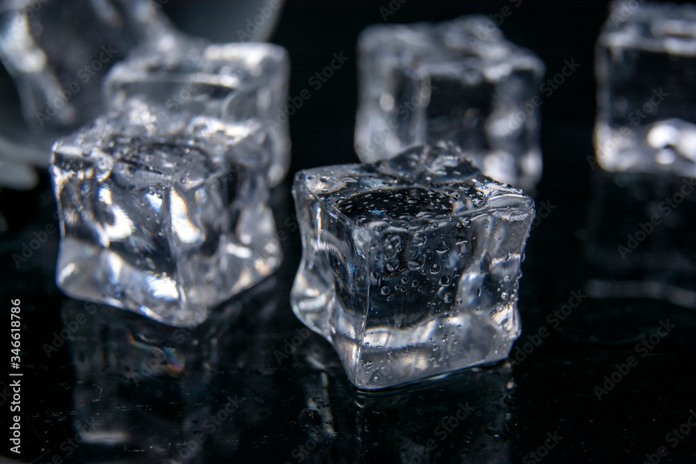 Obraz premium Ice cubes. Reflection of ice cubes on the black background of the table.