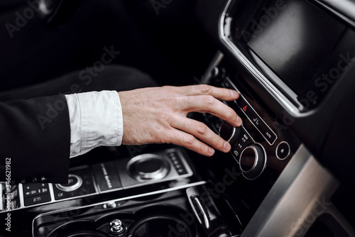 Businessman changing radio station while driving automobile