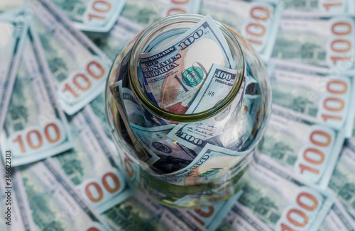 One hundred dollar bills in a glass jar