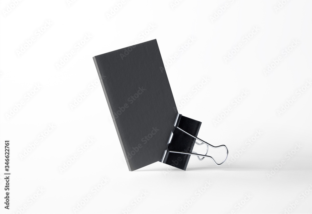 Obraz premium Blank black letterpress business cards stack in the clamp isolated on white high view as template for design presentation, logo embossing, mock-up etc.