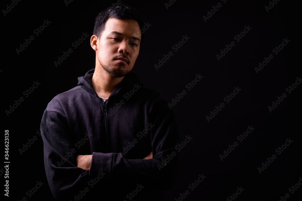 Portrait of serious young Asian man wearing hoodie with arms crossed