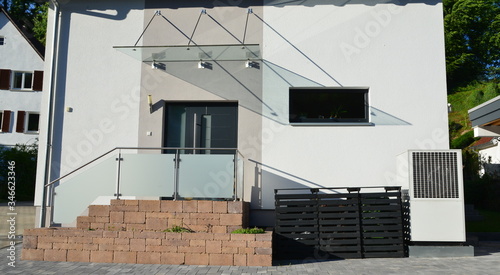 Luftwärmepumpe und Abfall-Sammelsystem vor einem Wohnhaus photo
