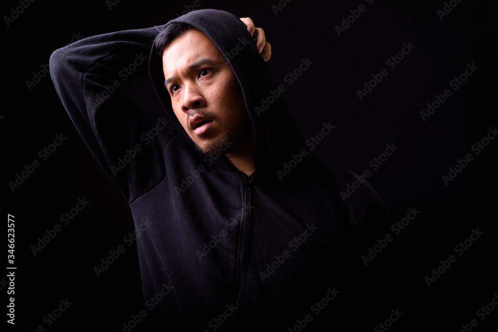 Portrait of stressed young Asian man in hoodie with hands behind back Portrait of stressed young Asian man in hoodie with hands behind back