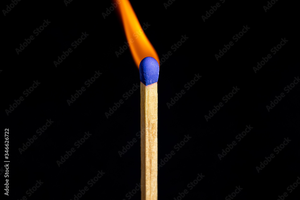 Single matchstick on fire in front of black background. Single matchstick on fire in front of black background.