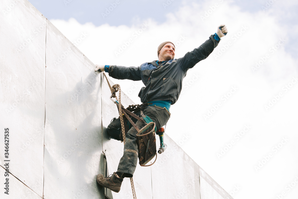 Industrial climber repair billboard. Risky job. Work on height. Metal construction. Electric screwdrive.
