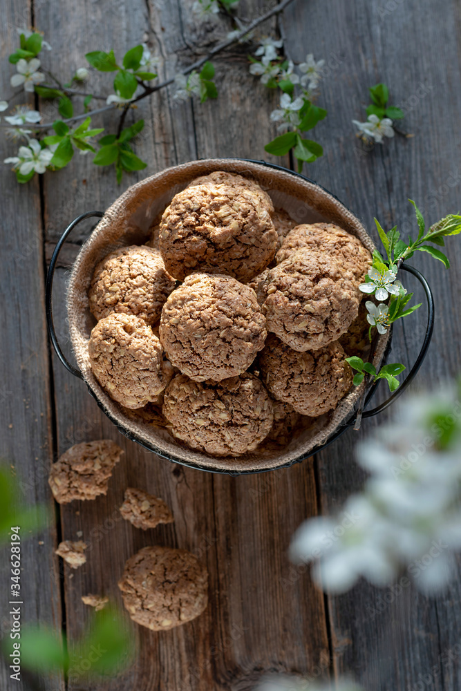 Homemade oatmeal cookies. Proper nutrition concept. Wood background. Spring flowers on the table. Homemade oatmeal cookies. Proper nutrition concept. Wood background. Spring flowers on the table.