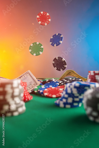 Casino background. Poker chips fall on the table. Against the background of chips and money. Creative light.