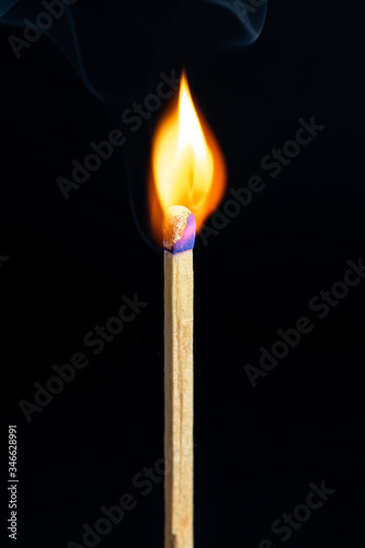 Single matchstick on fire in front of black background.