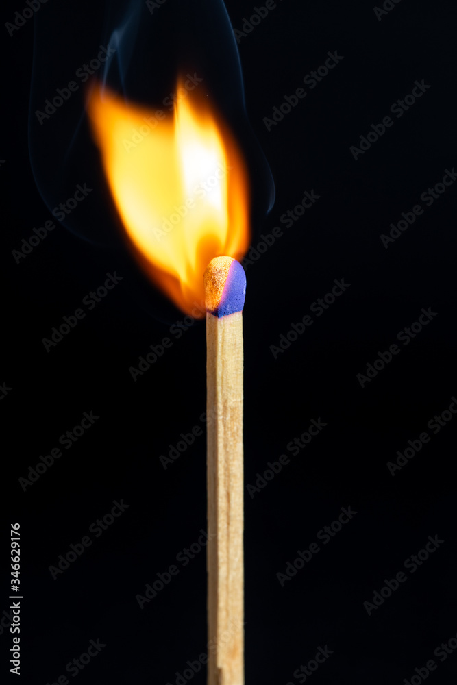 Single matchstick on fire in front of black background. Single matchstick on fire in front of black background.