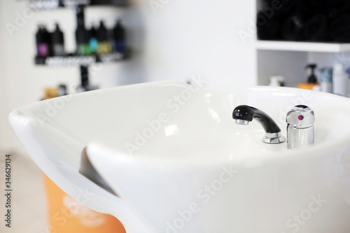 Professional white wash basin in the interior of a beauty salon. Barbershop wash basin, modern hairdresser and hair salon, barber shop for men.