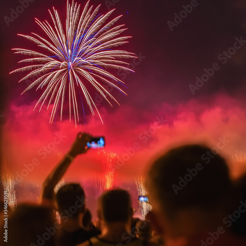Abstract blurred silhouettes of unrecognizable people back to us watche the fireworks, take photo, celebrate holiday