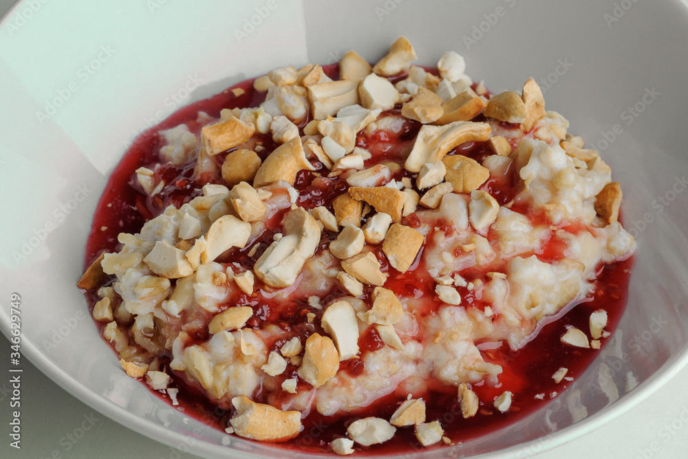 Porridge with jam and nuts on a white plate on a white background Porridge with jam and nuts on a white plate on a white background