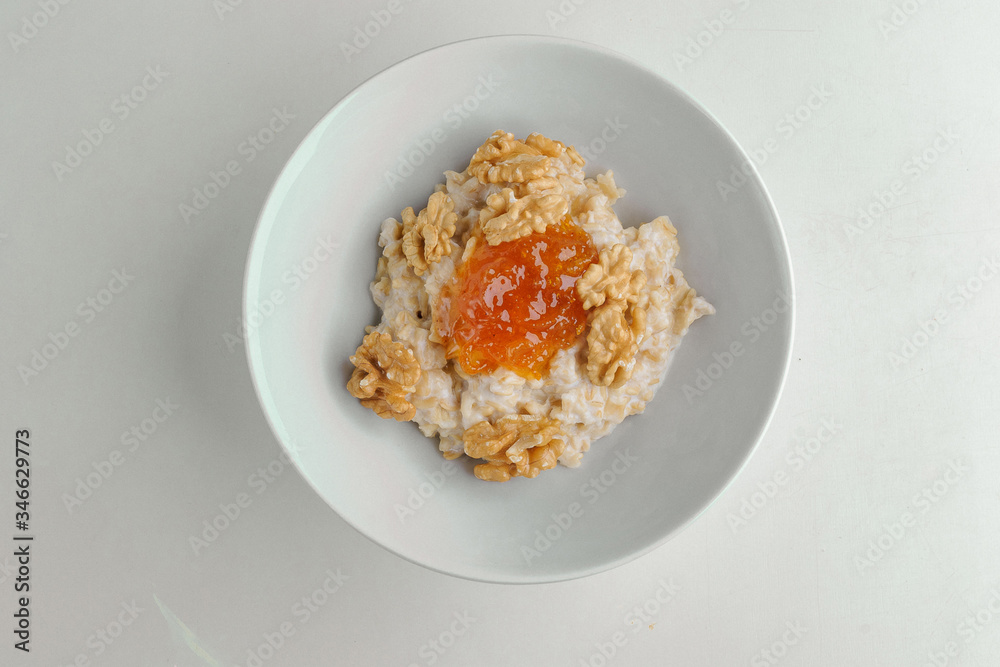 Porridge with jam and nuts on a white plate on a white background Porridge with jam and nuts on a white plate on a white background