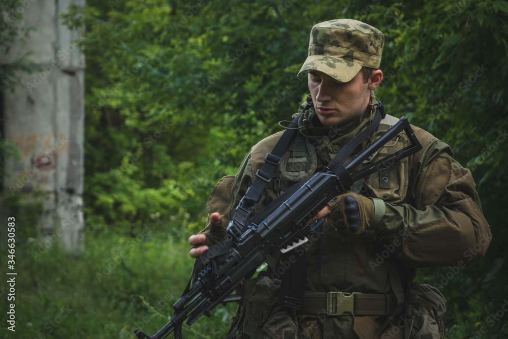 Fototapeta premium a soldier with a rifle makes his way through the forest