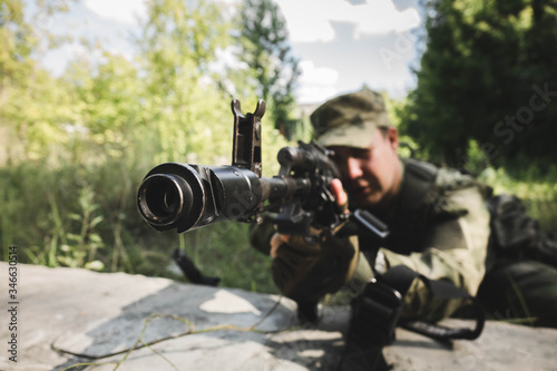 soldier lying down tries to aim and make a shot from the machine gun © Влад Астанин