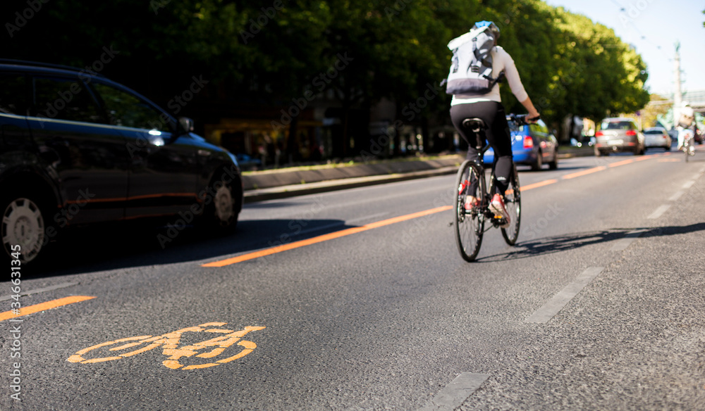 Bicycle lane and car traffic. Cycle lane with orange painted bike on asphalt. Ecological green urban transport.
Fahrradspur und Autoverkehr. Fahrrad Zeichen auf Straße. Ökologischer urbaner Verkehr.