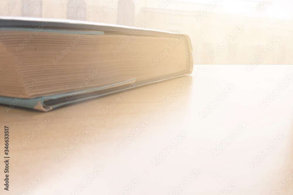 Heavy book on desk or table at window. Education background image with copy space. Heavy book on desk or table at window. Education background image with copy space.