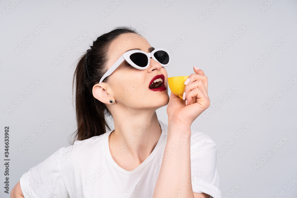 Girl in sunglasses with red lipstick on the lips, holding hands in a lemon and wants his bite, the concept of summer and rest Girl in sunglasses with red lipstick on the lips, holding hands in a lemon and wants his bite, the concept of summer and rest