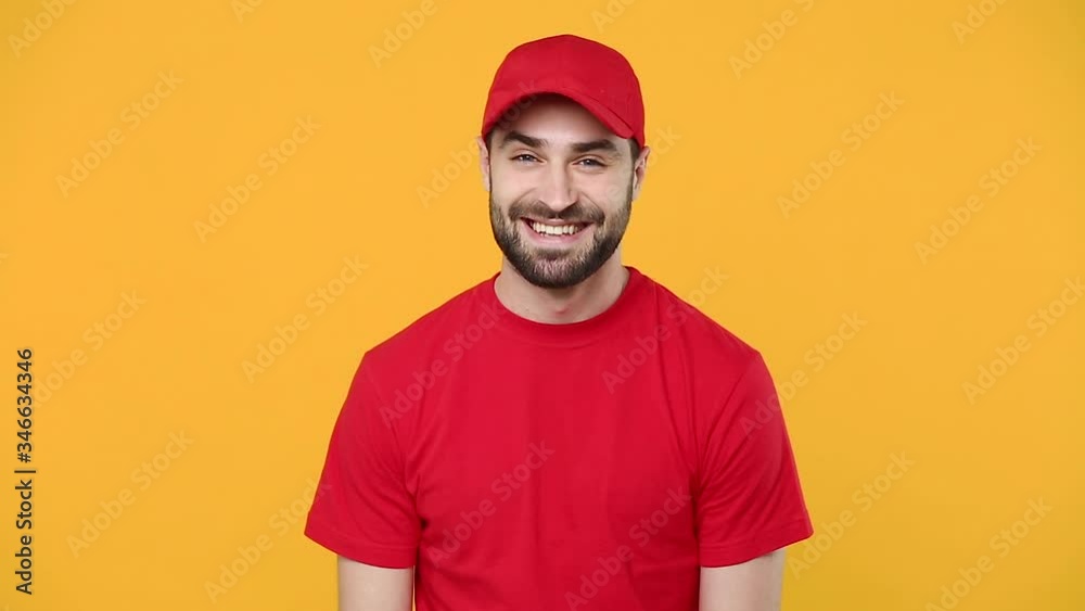 Smiling delivery young guy man in red cap blank t-shirt workwear looking camera isolated on yellow background studio Professional male deliveryman employee working as courier dealer Service concept Smiling delivery young guy man in red cap blank t-shirt workwear looking camera isolated on yellow background studio Professional male deliveryman employee working as courier dealer Service concept