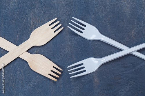 Zero waste concept. Wooden cutlery versus plastic cutlery. Eco-friendly disposable tableware made of bamboo wood and paper on a gray background. Caring for the environment. Recycling problem.