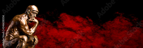 Photography A bronze replica statue of Rodin's Thinker on a smoky red background