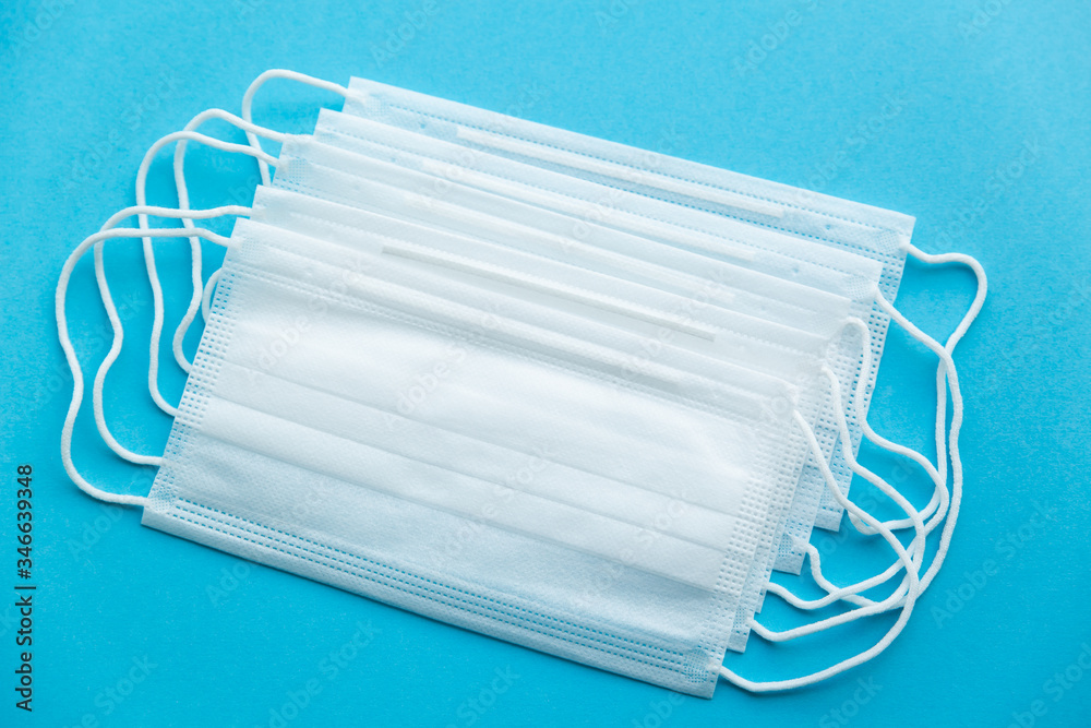 Stack of White protective medical masks on a blue background. The view from the top Stack of White protective medical masks on a blue background. The view from the top