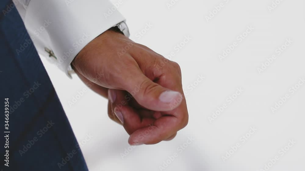 CU shot, slow motion: elegant young businessman in white shirt with cuff link holds hand on light background in modern office extreme close view CU shot, slow motion: elegant young businessman in white shirt with cuff link holds hand on light background in modern office extreme close view