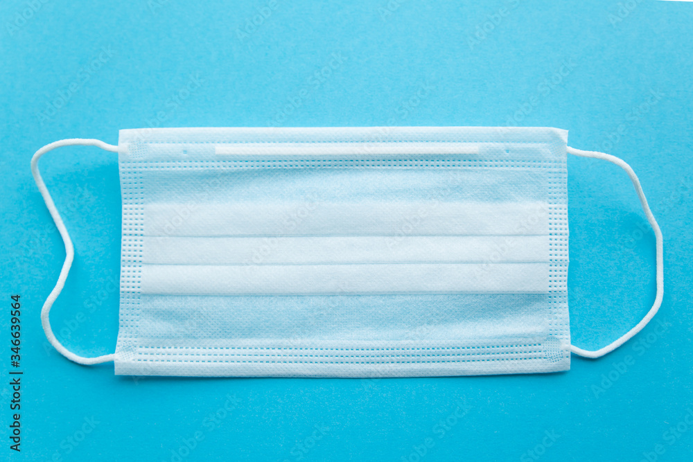 White protective medical mask on a blue background close-up.the view from the top White protective medical mask on a blue background close-up.the view from the top